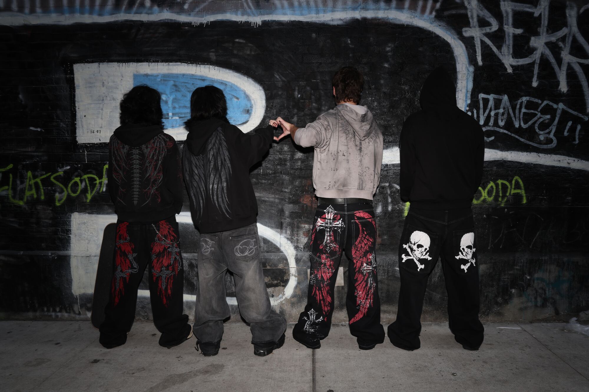 Two models in the Rapture drop: the Elden winged zip hoodie with skull denim and the Poser hoodie with plaid shorts